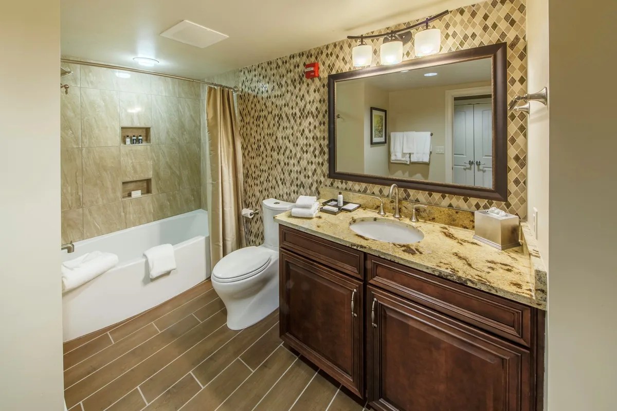 A bright, spa-like bathroom interior with a granite countertop, large mirror, and an oversized bathtub. The space offers a sense of tranquility and luxury, ideal for unwinding after a day of outdoor activity.