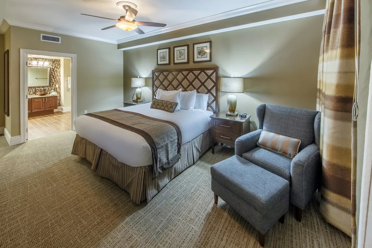 A cozy and serene bedroom with a plush king-size bed, armchair for reading, matching nightstands, and tasteful artwork on the walls. Soft natural light streams in, creating a tranquil retreat perfect for relaxation and restful sleep.